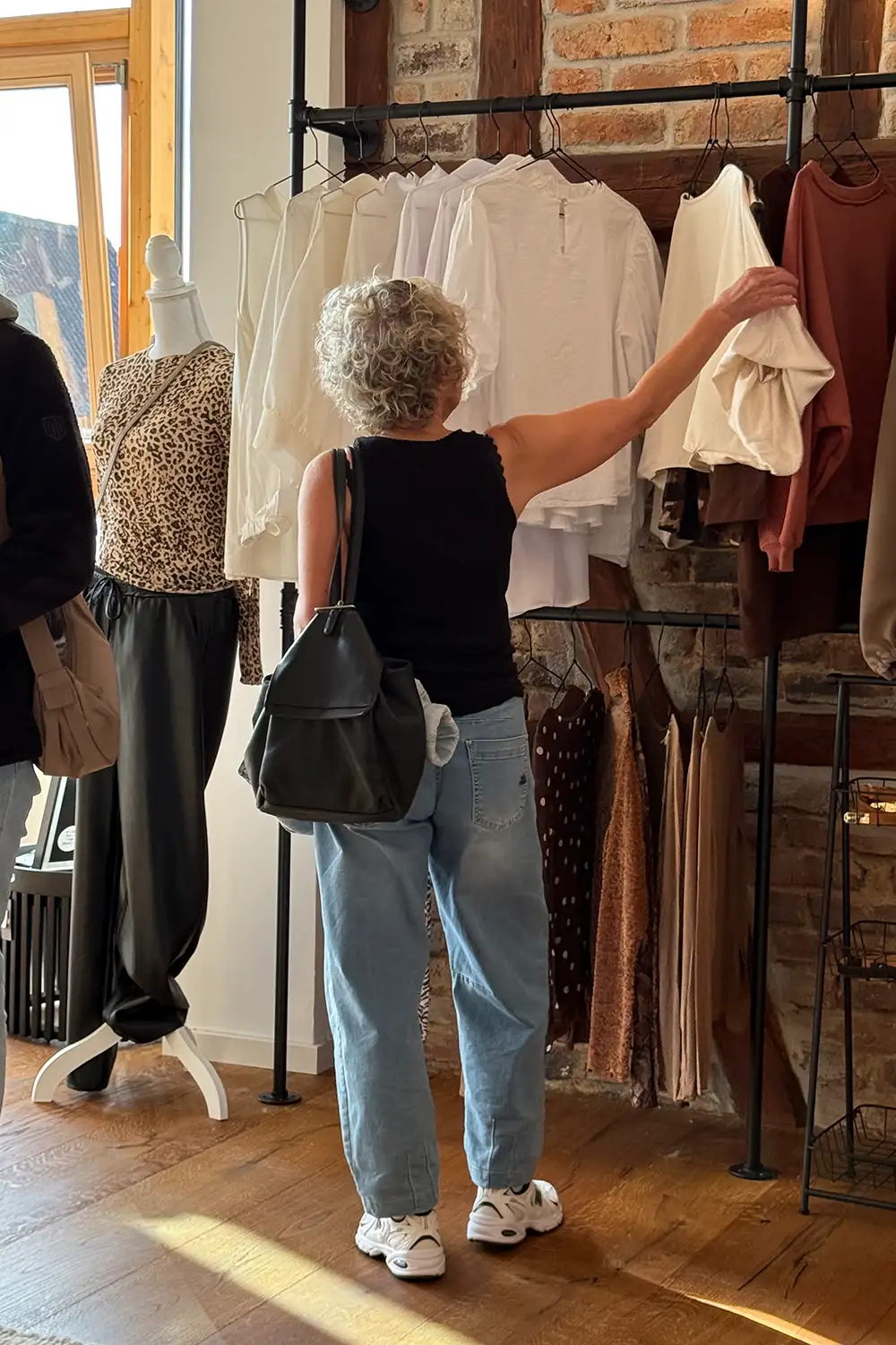 monas-store-huettenberg-mode-einkaufen Kundin stöbert durch die Damenbekleidung bei MONA’S Concept Store in Hüttenberg.